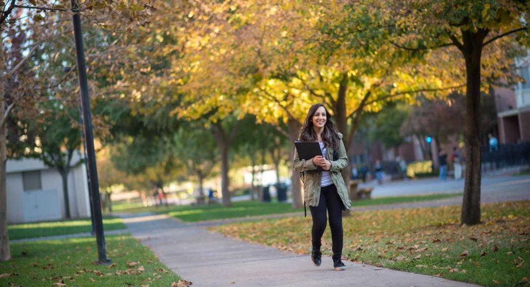 Smiling student walking on campus during fall