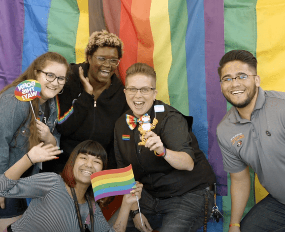 five students in front of rainbow flag